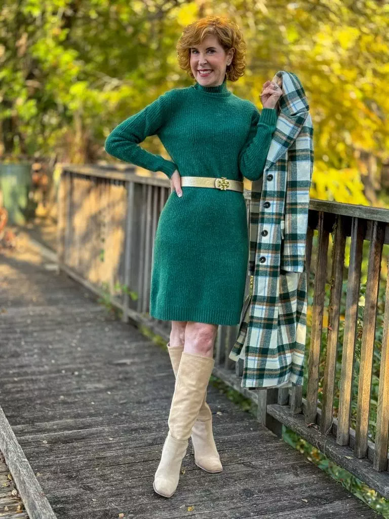 woman wearing talbots green sweater dress holding walmart free assembly plaid coat in one hand beside her to the left side